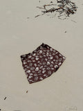Brown fabric with white shell patterns in the shape of a Skort for women to wear over their swimwear that is made from Terry towelling on a sandy surface